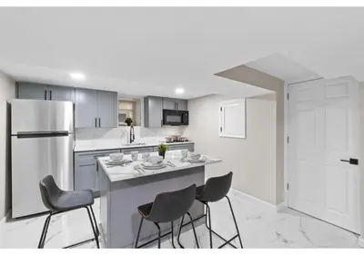 a kitchen with a island with chairs and a refrigerator at Epic Spa & Play Retreat NYC EWR Sleeps 30! in Bayonne