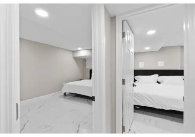 a white bedroom with a bed and a window at Epic Spa & Play Retreat NYC EWR Sleeps 30! in Bayonne