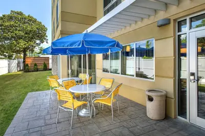 a table and chairs with a blue umbrella on a patio at Fairfield Inn & Suites by Marriott New Castle in New Castle