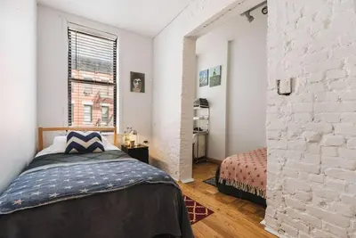 a bedroom with a bed and a brick wall at East Village Townhouse in New York