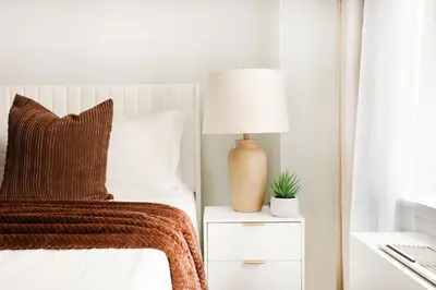 a bedroom with a bed with a lamp on a night stand at 73-1004 New Studio UWS Doorman Gym in New York
