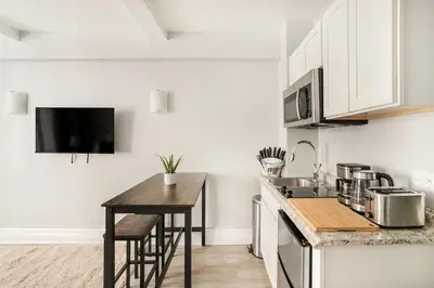 a kitchen with white cabinets and a wooden counter top at 73-1004 New Studio UWS Doorman Gym in New York