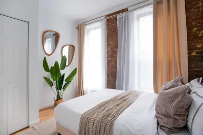 a bedroom with a white bed and a brick wall at 153-1G Newly Renovated 2BR Lower East Side in New York