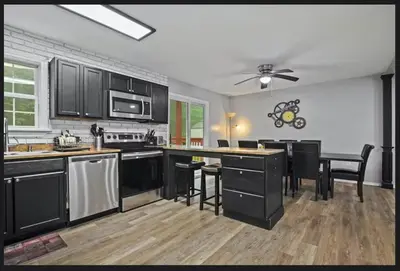 a kitchen with black cabinets and a table and chairs at Horatio Hideaway Pocono Escape in Tobyhanna