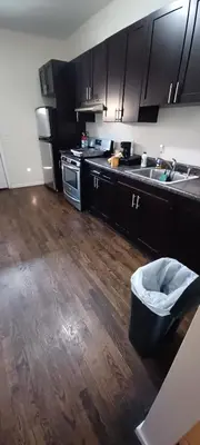 a kitchen with black cabinets and a wooden floor at willoughby inn in Newark