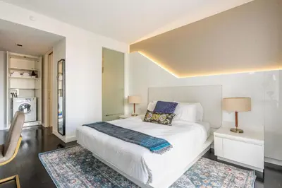 a bedroom with a large white bed and two rugs at Financial District 1br w WD gym elevator NYC-1360 in New York