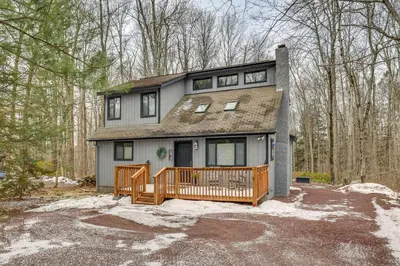a house with a wooden deck in the woods at Pocono Pines Home with Private Hot Tub! in Pocono Pines