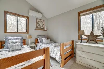 two twin beds in a room with two windows at Pocono Pines Home with Private Hot Tub! in Pocono Pines