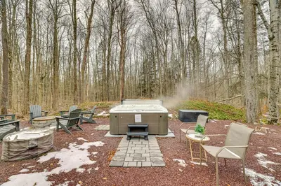 a fire pit with a grill and chairs and trees at Pocono Pines Home with Private Hot Tub! in Pocono Pines