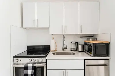 a white kitchen with a sink and a microwave at 444-2E Modern 2BR Hell's Kitchen in New York