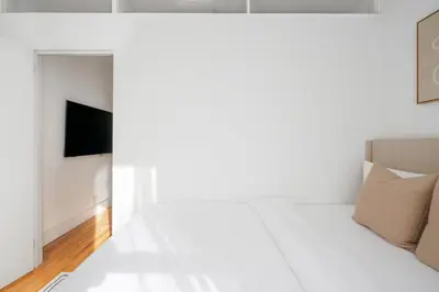 a white living room with a couch and a television at 444-2E Modern 2BR Hell's Kitchen in New York