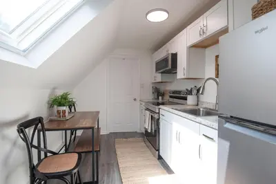 a kitchen with white cabinets and a wooden table at The Wren's Nest in Birdsboro