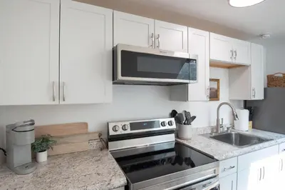 a kitchen with white cabinets and a stainless steel stove at The Wren's Nest in Birdsboro