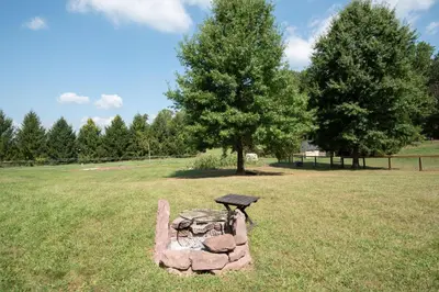 a stone fire pit with a picnic table in a field at The Wren's Nest in Birdsboro