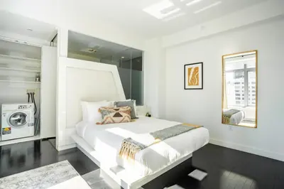 a white bedroom with a bed and a washing machine at Financial District 1br w WD gym elevator NYC-1362 in New York