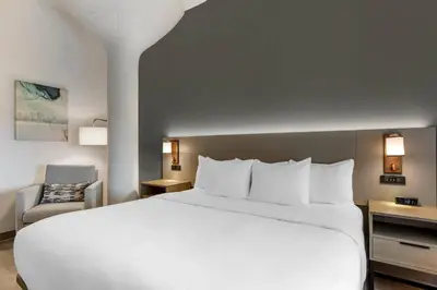 a hotel room with a white bed and a chair at Comfort Inn & Suites Newark Liberty International Airport in Newark