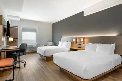 a hotel room with two beds and a desk at Comfort Inn & Suites Newark Liberty International Airport in Newark