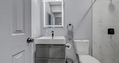 a white bathroom with a toilet and a sink at Peaceful Pocono Home with Hot Tub, gym, & office in Long Pond