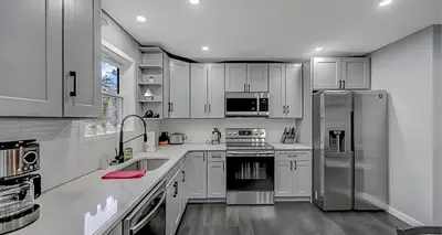a kitchen with white cabinets and a stainless steel refrigerator at Peaceful Pocono Home with Hot Tub, gym, & office in Long Pond