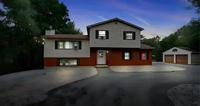 a house with a driveway in front of it at Peaceful Pocono Home with Hot Tub, gym, & office in Long Pond