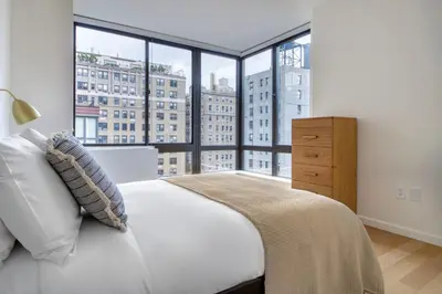 a bedroom with a white bed and a large window at Upper West Side 2br w rooftop gym nr park NYC-1216 in New York