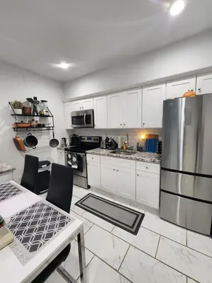 a kitchen with white cabinets and a stainless steel refrigerator at Zen Oasis Room in Newark