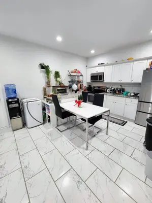 a white kitchen with a table and chairs in it at Zen Oasis Room in Newark