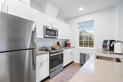 a kitchen with white cabinets and a stainless steel refrigerator at Modern 2BR 2BA Condo Sleeps 8 with Gym Laundry 20 Min to NYC in Jersey City