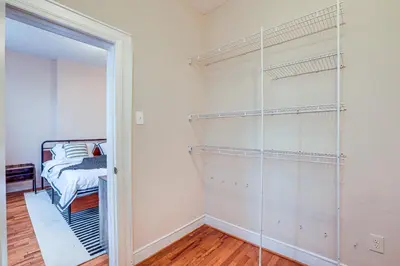 a walk in closet with glass shelves and a bed at Comfy Bayonne Townhome about 11 Mi to NYC Attractions in Bayonne