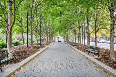 a walkway with benches and trees in a park at FiDi 1br w game room resident-only speakeasy NYC-1346 in New York