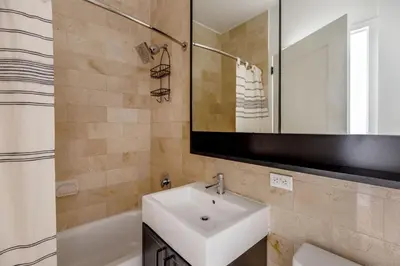 a bathroom with a sink and a mirror and a tub at FiDi 1br w gym doorman lounge nr park NYC-1344 in New York