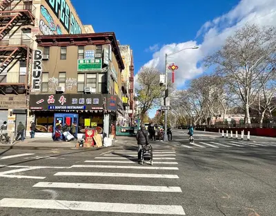 a person with a stroller crossing the street at a crosswalk at moon lotus abode(\u6708\u84ee\u5c45) in New York