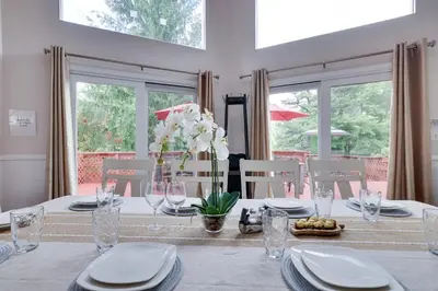 a dining room table with white plates and flowers on it at Cozy cottage in the heart of pocono in Long Pond