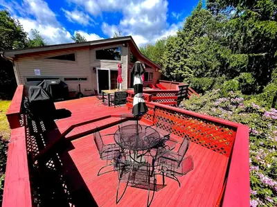 a deck with a table and chairs on a house at Cozy cottage in the heart of pocono in Long Pond