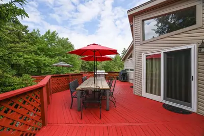 a wooden deck with a table with an umbrella at Cozy cottage in the heart of pocono in Long Pond