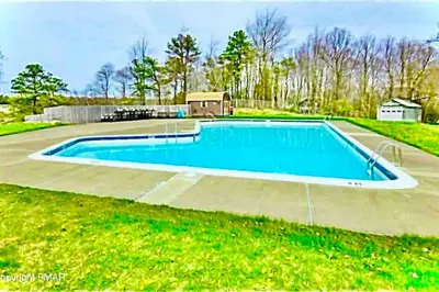 a large swimming pool in a yard with a house at Cozy cottage in the heart of pocono in Long Pond