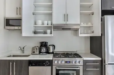 a kitchen with white cabinets and a stove top oven at Hudson Yards 1br w gym wd nr penn station NYC-1308 in New York