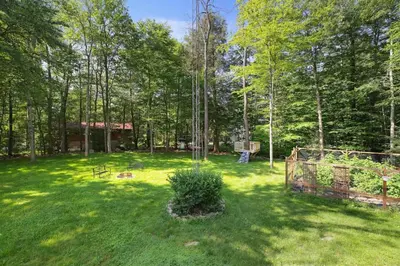 a yard with a fence and a bush in the grass at Comfy Log Cabin Family & Pet Kind by State & Waterparks! in Tobyhanna