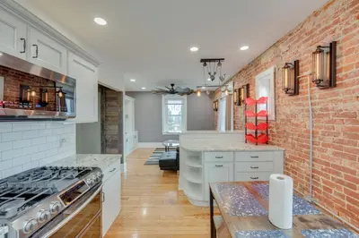 a kitchen with white cabinets and a brick wall at 15 Mi to Amish Village Cozy Lancaster Apt! in Lancaster