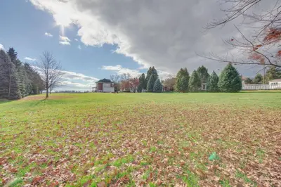 a large field of grass with a house in the background at 15 Mi to Amish Village Cozy Lancaster Apt! in Lancaster