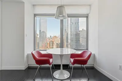 a table and two red chairs in a room with a window at Financial District 1br w WD gym elevator NYC-1368 in New York