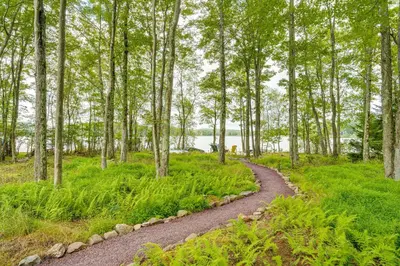 a winding path through a forest with trees at Lakefront Poconos Family Home with Pool Access in Pocono Lake