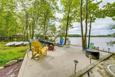 a group of chairs sitting on a patio next to a lake at Lakefront Poconos Family Home with Pool Access in Pocono Lake