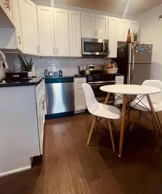 a kitchen with white cabinets and a table and chairs at Bright, Cozy Room Near Center City Philadelphia and Museums in Philadelphia