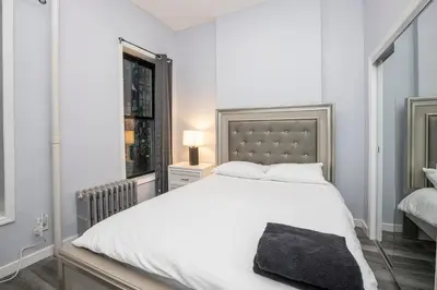 a bedroom with a white bed and a window at Spectacular Times Square 5 Bedroom Duplex Oasis in New York
