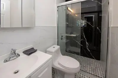a white bathroom with a toilet and a glass shower at Spectacular Times Square 5 Bedroom Duplex Oasis in New York