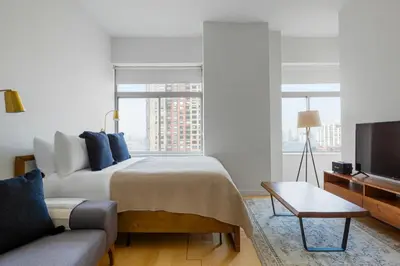 a bedroom with a bed and a couch and a tv at Financial District studio w gym doorman NYC-1289 in New York
