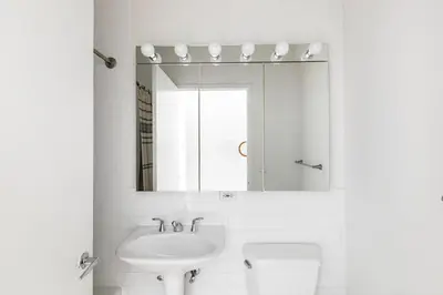 a white bathroom with a sink and a mirror at Financial District studio w gym doorman NYC-1289 in New York