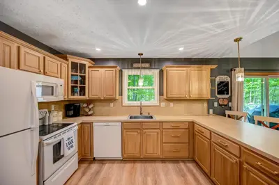 a kitchen with wooden cabinets and a white appliance at 1 Mi to Beach Pocono Lake Chalet with Decks in Pocono Lake