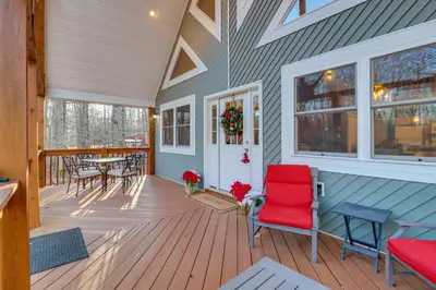 a porch with a red chair and a table at 1 Mi to Beach Pocono Lake Chalet with Decks in Pocono Lake
